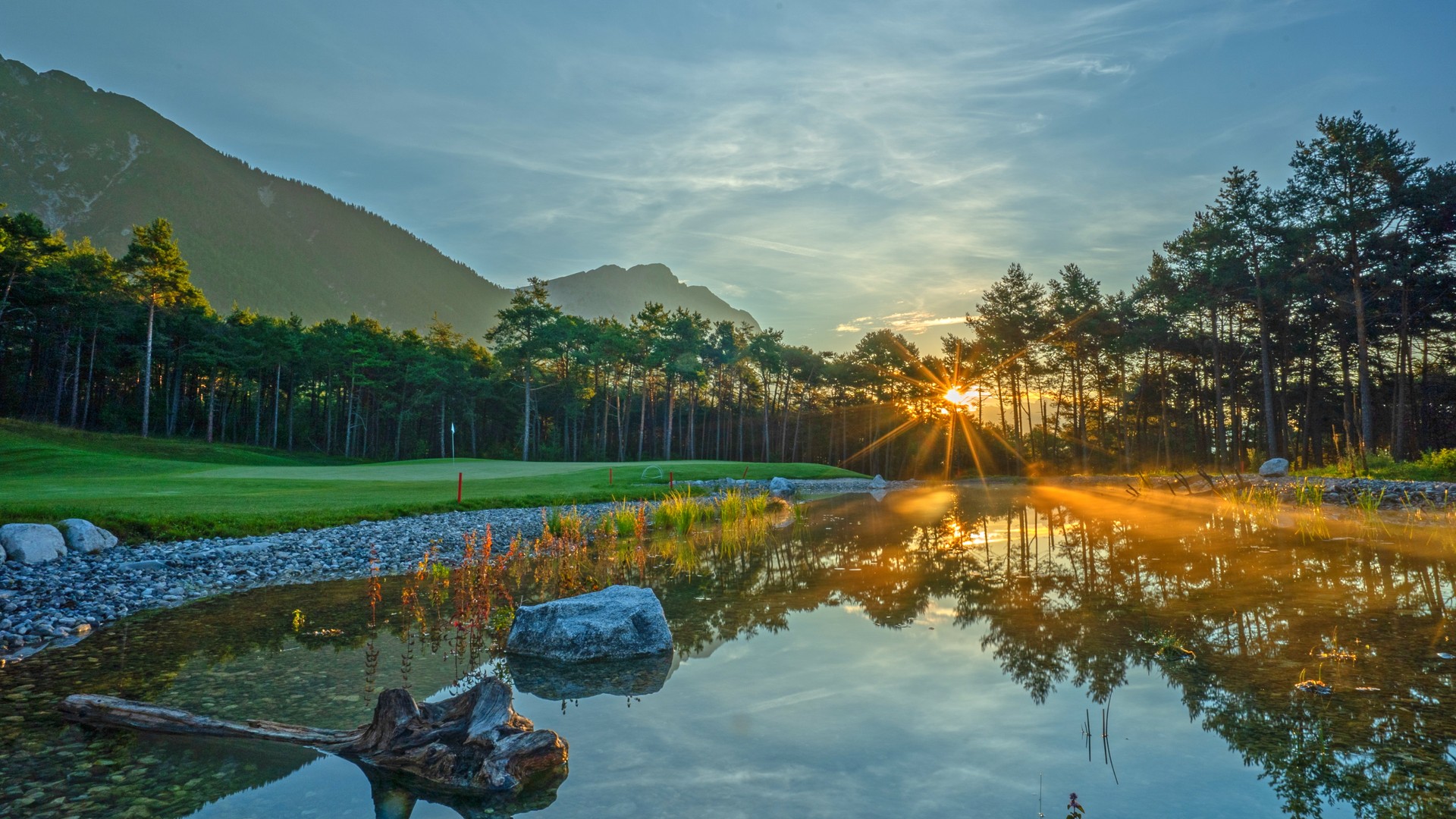 Sonnenaufgang mit Spiegelung im Wasser am Golfplatz Mieming